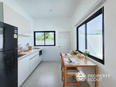 Bright modern kitchen with sleek appliances and dining area, featuring large windows for natural light.