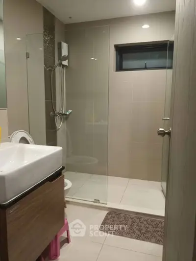 Modern bathroom with glass shower and sleek fixtures in contemporary home.