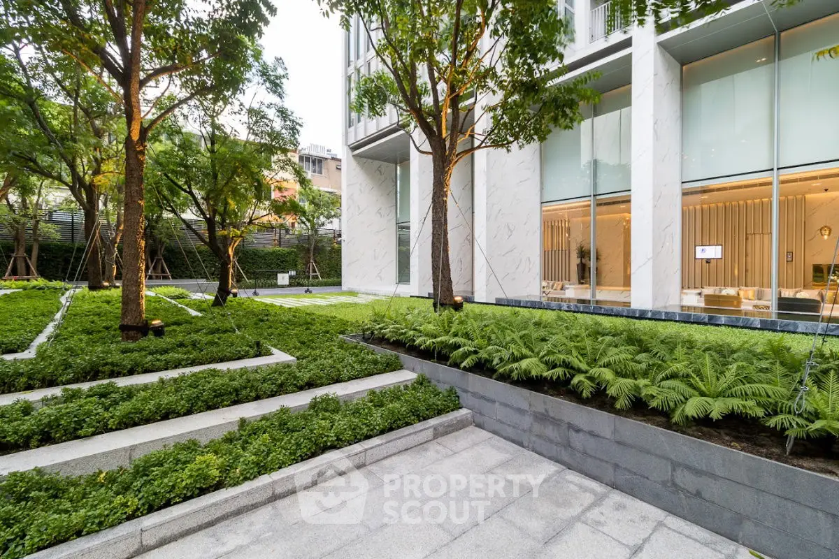 Luxurious modern building exterior with lush landscaped garden and sleek architectural design.
