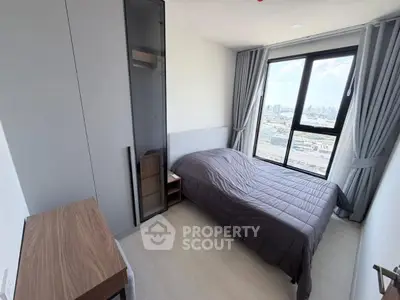 Modern bedroom with city view, featuring sleek furniture and large window for natural light.