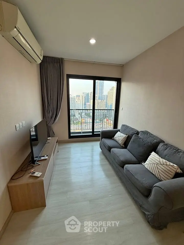 Modern living room with city view, featuring cozy sofa and sleek TV setup.