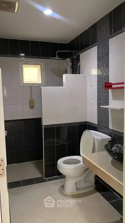 Modern bathroom with sleek black and white tiles and contemporary fixtures.