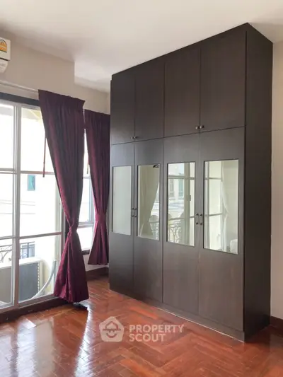 Spacious bedroom with elegant dark wood wardrobe and large windows