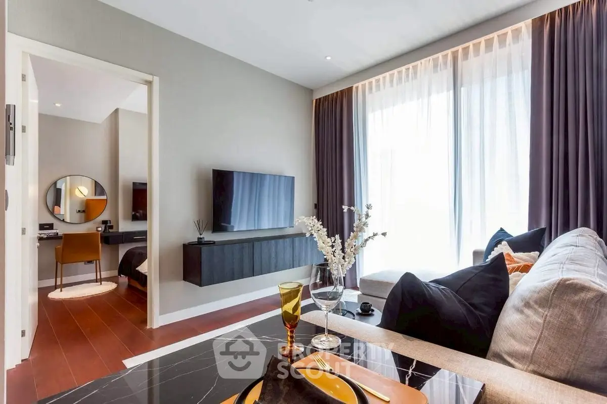 Modern living room with elegant decor and large window, featuring a cozy seating area and stylish TV setup.