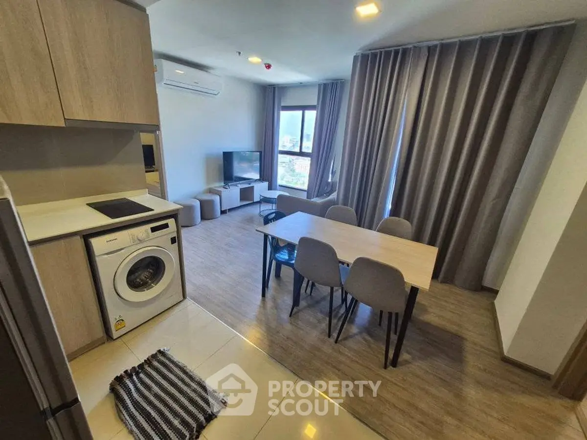 Modern open-plan living room with dining area and washing machine in stylish apartment.