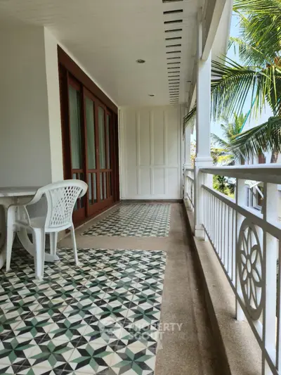 Charming balcony with patterned tiles and tropical view, perfect for relaxation.
