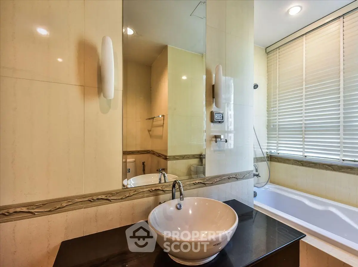 Luxurious bathroom with modern sink and bathtub, elegant design and ample natural light.