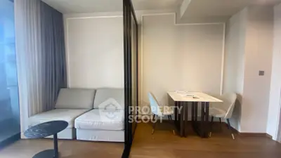 Modern living room with cozy sofa and elegant dining area, featuring sleek design and natural light.