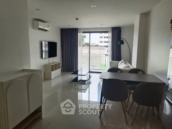 Modern living room with sleek furniture and large window offering natural light.