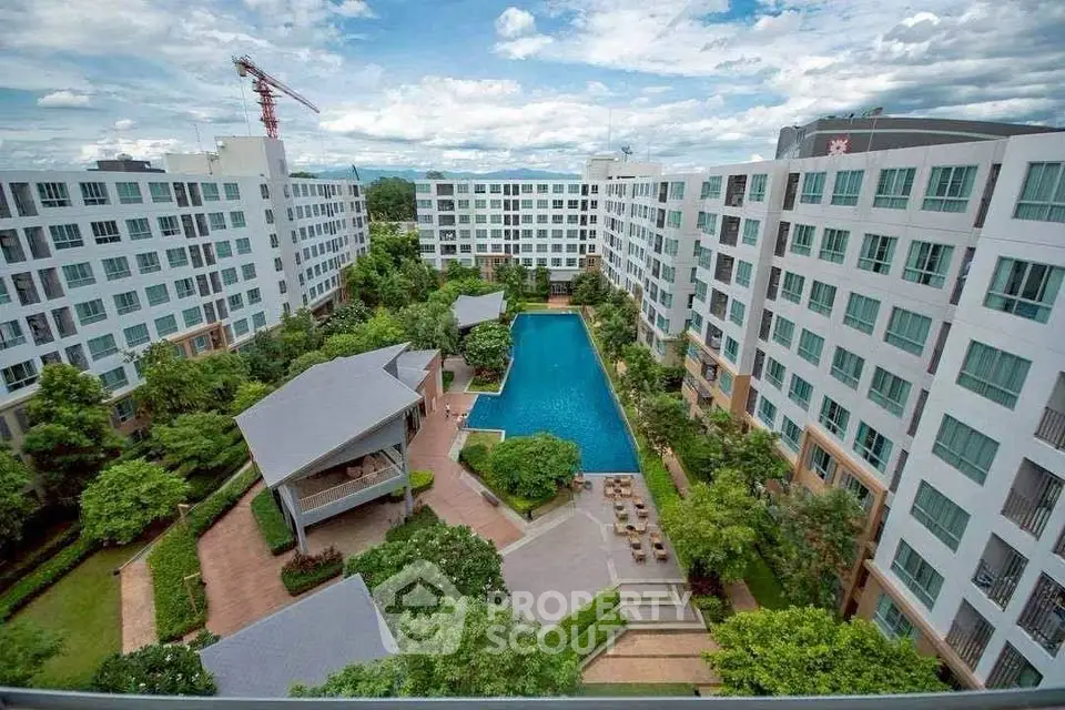 Stunning aerial view of modern apartment complex with central pool and lush gardens.