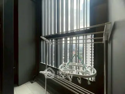 Modern balcony with city view and drying rack in high-rise apartment.