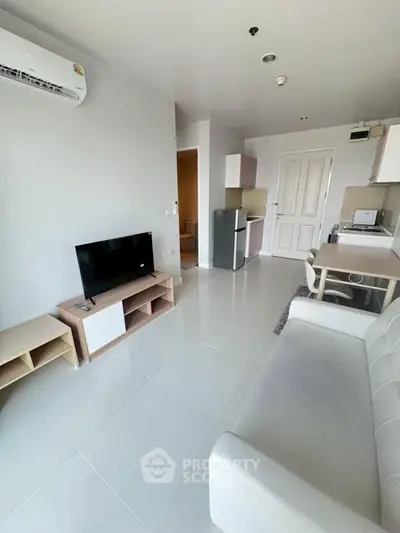 Modern living room with sleek furniture and open kitchen layout in a bright apartment.
