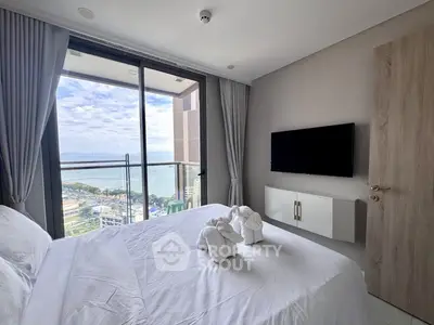 Luxurious bedroom with stunning sea view from balcony in modern high-rise apartment.