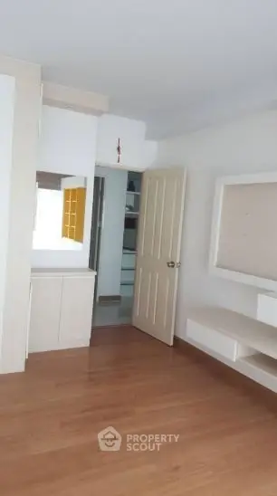 Spacious modern bedroom with wooden flooring and built-in storage solutions.