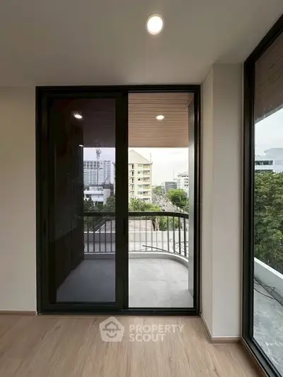 Modern apartment with large glass doors leading to a spacious balcony offering city views.