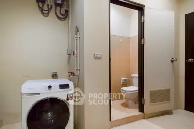 Compact laundry area with washing machine adjacent to a small bathroom