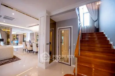 Luxurious open-plan living room with elegant dining area and wooden staircase