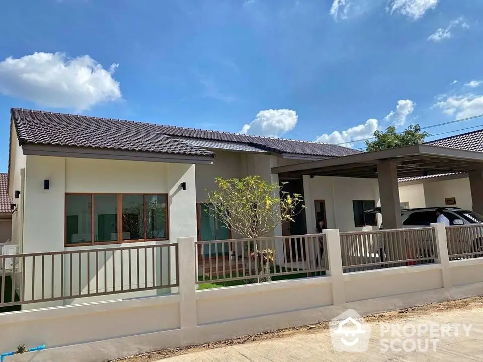 Charming single-story house with modern design and spacious driveway under clear blue sky.