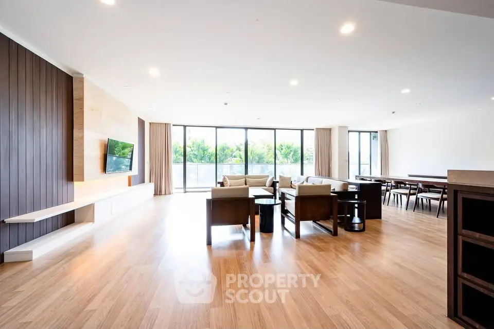 Spacious modern living room with large windows and elegant wooden flooring.