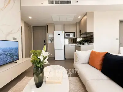 Modern living room with open kitchen, stylish decor, and city view from window.