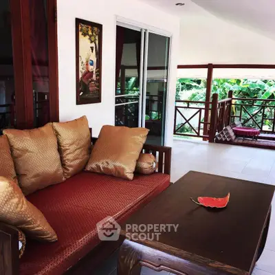 Charming tropical balcony with cozy seating and lush garden view, perfect for relaxation.