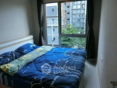 Cozy bedroom with large window offering urban view in modern apartment