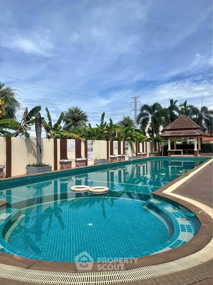 Luxurious outdoor swimming pool with tropical landscaping and gazebo, perfect for relaxation and leisure.