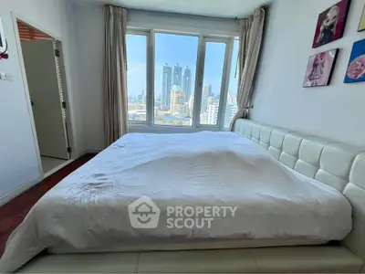 Spacious bedroom with city view and modern decor in high-rise apartment.