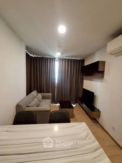 Modern living room with cozy sofa, wall-mounted TV, and elegant curtains in a stylish apartment.