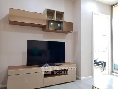 Modern living room with sleek TV unit and wall-mounted storage in a bright apartment.