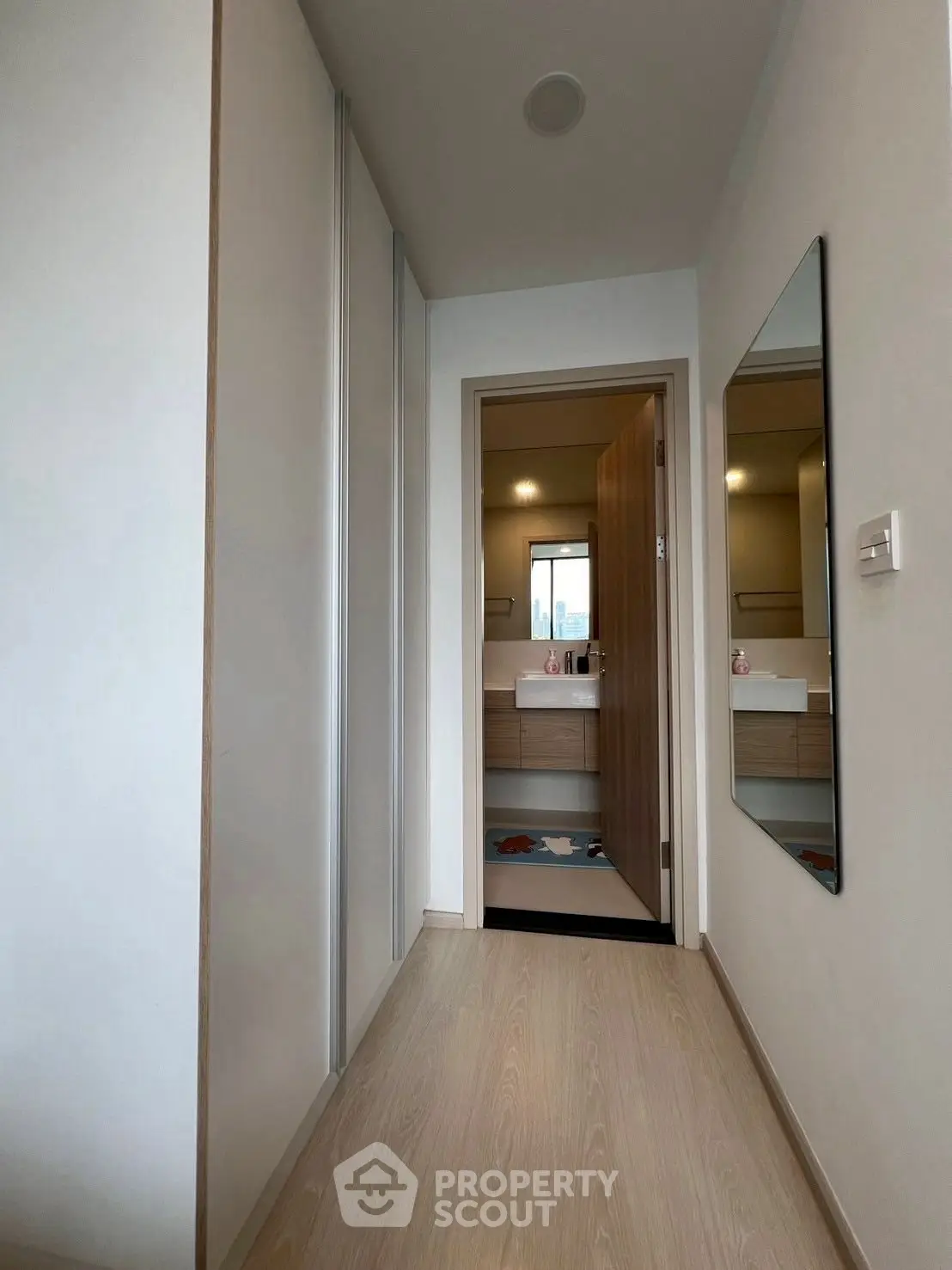 Modern hallway leading to a stylish bathroom with sleek fixtures.