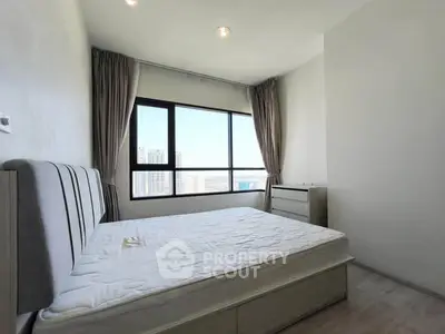 Bright bedroom with large window and city view, featuring a comfortable bed and modern decor.