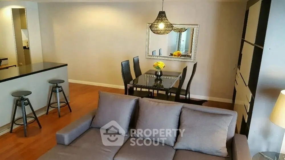 Modern living room with stylish dining area and cozy sofa, featuring elegant lighting and hardwood floors.