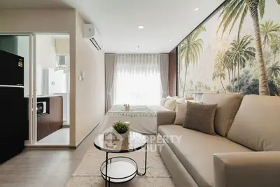 Modern living room with tropical mural and open kitchen layout in stylish apartment.