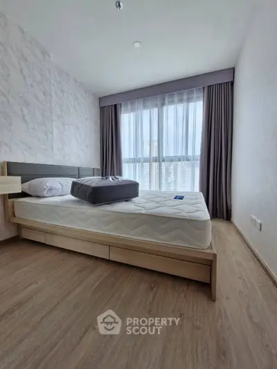 Spacious bedroom with modern design and large window offering natural light.