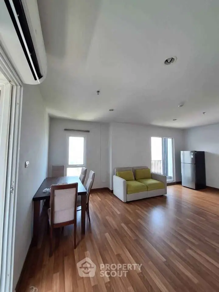 Spacious living room with modern furniture and wooden flooring in a bright apartment.