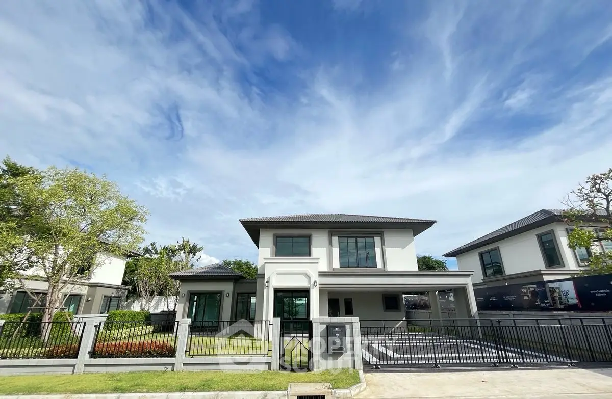 Modern two-story house with spacious front yard and driveway under a clear blue sky.