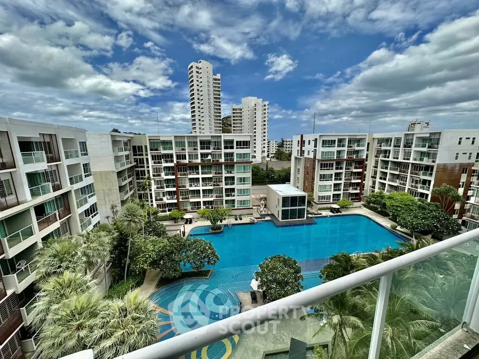 Luxurious apartment complex with stunning pool and lush greenery under a vibrant sky.
