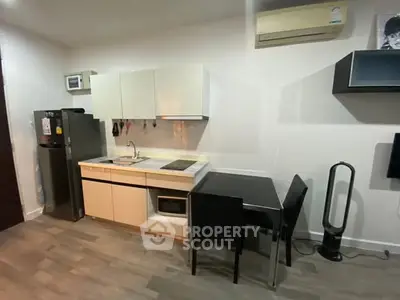 Modern compact kitchen with sleek cabinetry and dining area in cozy apartment.