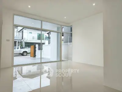 Spacious modern living room with large glass doors and glossy tiled floors, offering a bright and airy ambiance.
