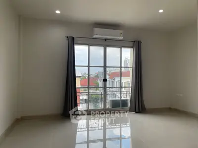 Spacious room with large window and city view, perfect for modern living.