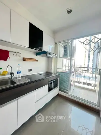 Modern kitchen with sleek cabinetry and balcony access in urban apartment