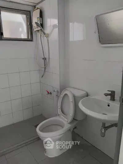 Compact bathroom with shower, toilet, and sink in a tiled setting.