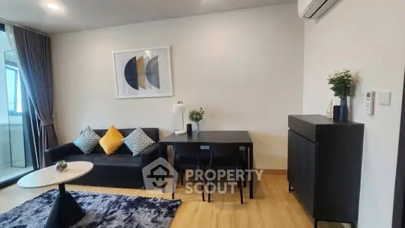 Modern living room with stylish decor and balcony view, featuring sleek furniture and elegant lighting.