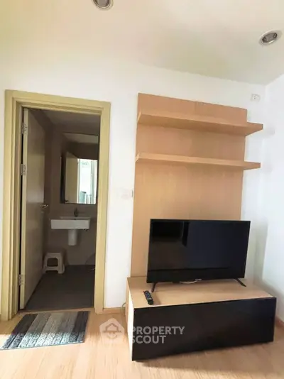 Cozy living room with TV and open bathroom view in modern apartment
