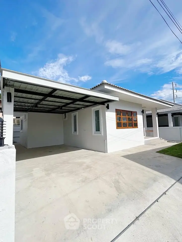 Modern single-story home with spacious driveway and covered carport under a clear blue sky.