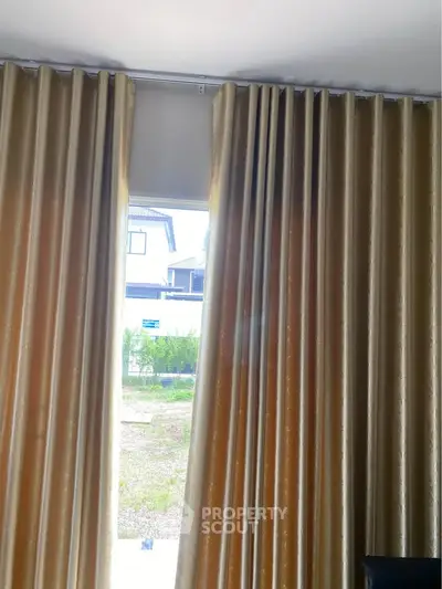Elegant curtains framing a window with a view of a modern house exterior, perfect for stylish home interiors.