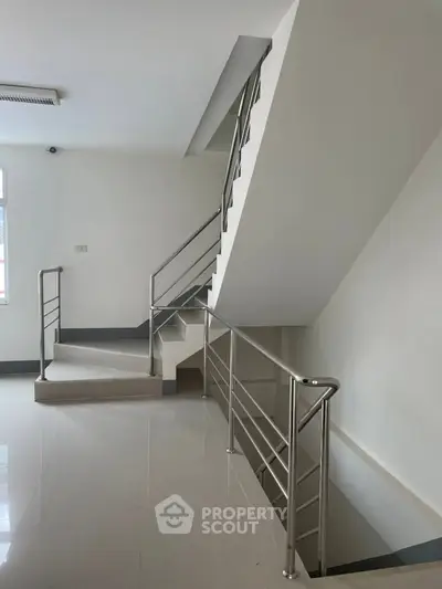 Modern staircase with sleek metal railing in a bright, minimalist interior space.