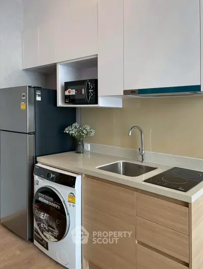 Modern kitchen with sleek appliances and compact design, featuring a washing machine and microwave.
