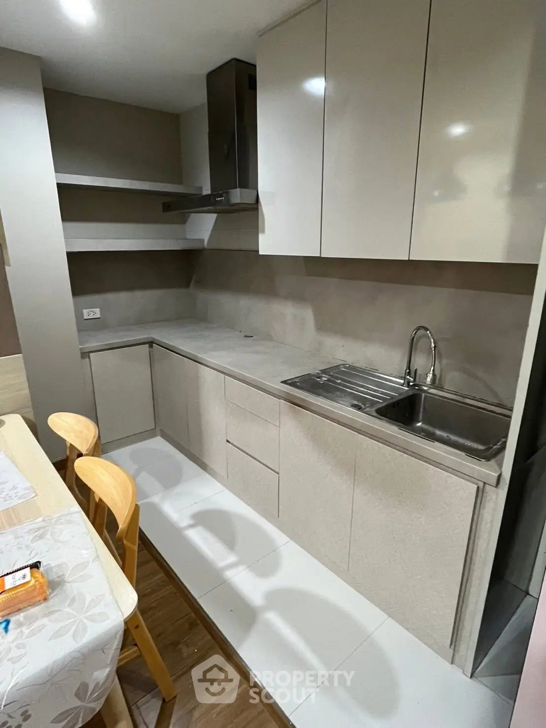 Modern kitchen with sleek cabinetry and stainless steel sink in a cozy apartment.
